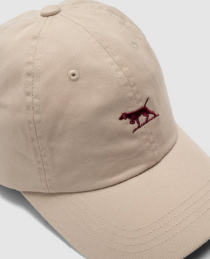 The Rodd & Gunn Gunn Cap is a beige baseball cap made from heavy-duty cotton twill, featuring a small embroidered red dog logo on the front. Its charm is enhanced by a curved brim and stitching details, all standing out against a plain white background.