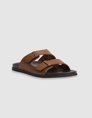 The Rodd & Gunn Kendrick Place Slide, featuring brown leather straps and a flexible rubber sole, is displayed against a plain gray background.