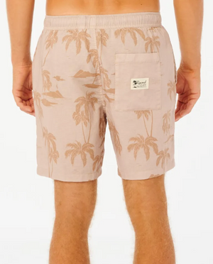 A person is seen from behind wearing Rip Curl Mod Tropics Volley shorts with a tropical palm tree design. These linen/cotton blend shorts feature an elastic waist, a back pocket with a small white label, and reveal the skin on the legs.