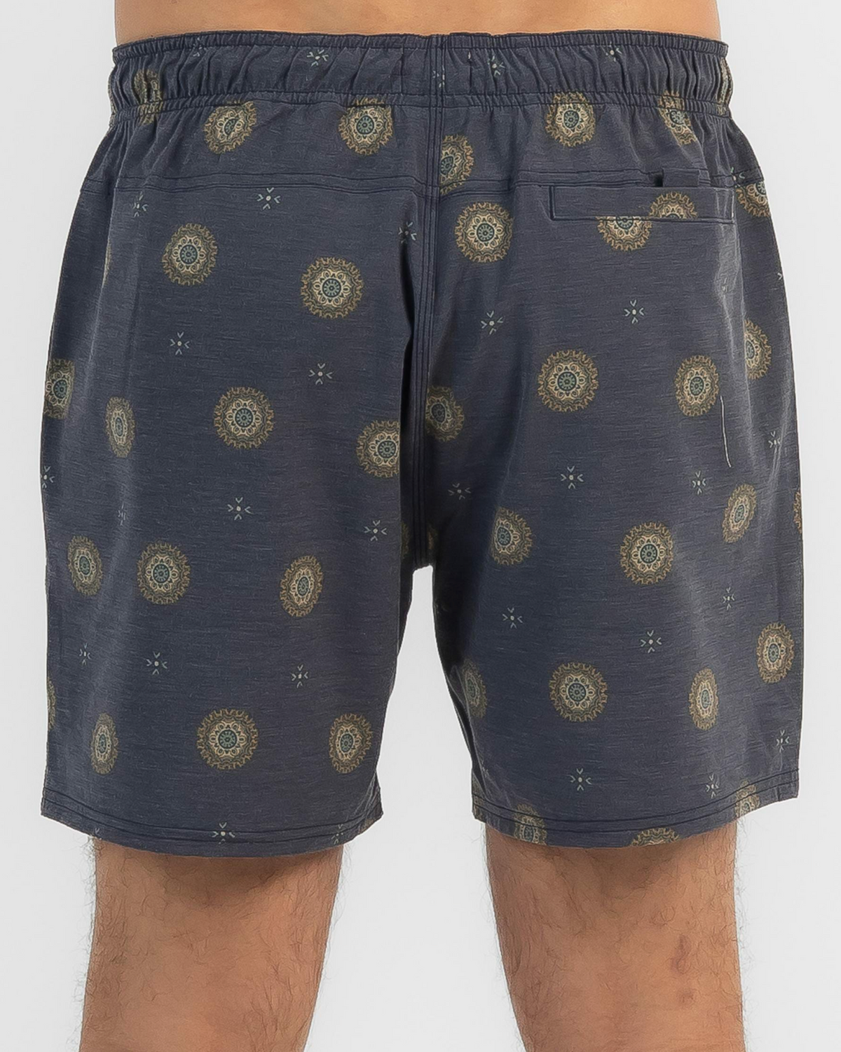 Someone is wearing Rip Curl Party Pack Volley Shorts in dark gray with a circular mandala-like print. These casual shorts have an elastic waist, small back pocket, and mid-thigh length. Photo is taken from the back.