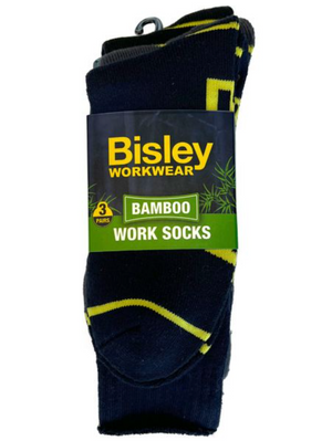 The Bisley Bamboo Work Sock 3pk includes three pairs made from breathable, moisture-wicking material. The dark socks feature yellow accents and come in a package with a dark blue and green design adorned with bamboo illustrations.