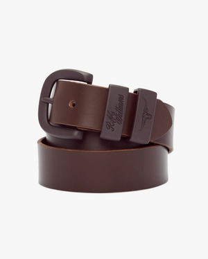 A coiled RM Williams Drover 1 1/2 Belt, crafted from brown vegetable-tanned leather with a dark buckle, is displayed against a plain white background. The belt features a polished finish and debossed Longhorn logo on the loops near the buckle.