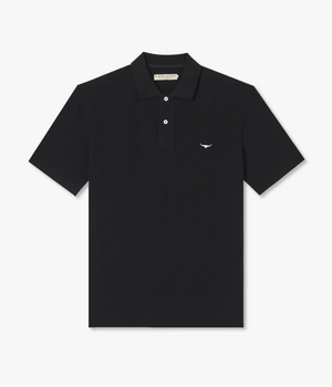 The RM Williams Rod Polo is a plain black cotton pique polo shirt with a classic ribbed collar and three-button placket. It features a small white Longhorn embroidery on the left side of the chest, adding a distinctive touch to its design.