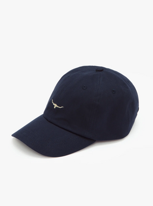 An RM Williams Mini Longhorn Cap in navy blue, featuring a small, minimalist white longhorn logo embroidered on the front. The classic twill cap boasts a curved brim and is made of soft fabric material, set against a plain white background.