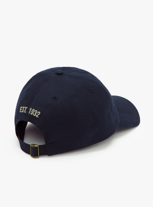 The RM Williams Mini Longhorn Cap features a navy blue classic twill design, complete with an adjustable strap and buckle at the back. The text "EST. 1932" is embroidered in yellow above the strap, giving it a timeless style that is accentuated when viewed from the back.