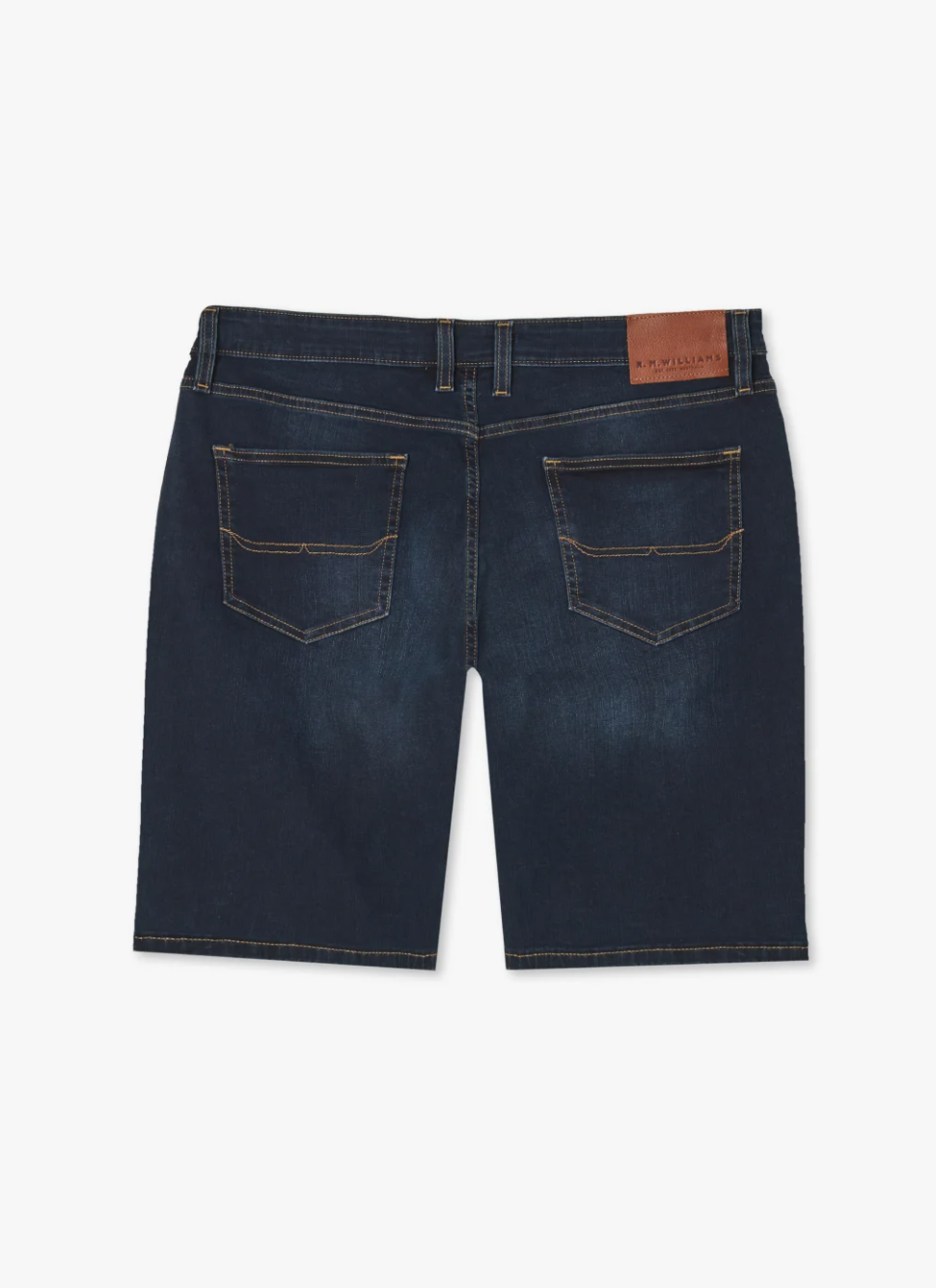 Back view of RM Williams Nicholson Short in dark blue stretch denim with a low-rise waistband, featuring Classic 5 pocket styling and visible stitching. The shorts have belt loops and a brown leather patch on the right side of the waistband. The fabric appears slightly worn or distressed.