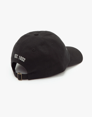 The RM Williams Script Cap in black has "Est. 1932" embroidered on the back in white, is crafted from cotton twill, and includes an adjustable strap with a metal buckle, presented on a white background.