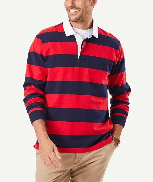 A man wearing a Gazman Block Stripe Rugby, which features red and navy horizontal stripes and a white collar, paired with khaki pants. The cotton shirt enhances his casual style as he smiles, looking to the side with one hand in his pocket and the other relaxed by his side.