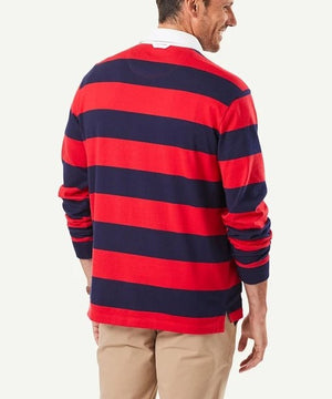 A man is seen from the back wearing the Gazman Block Stripe Rugby, a regular fit, long-sleeve jumper with bold horizontal stripes in red and navy blue. He pairs it with beige pants and a white-collared shirt underneath. Made from soft cotton, the ensemble stands out against the plain white background.