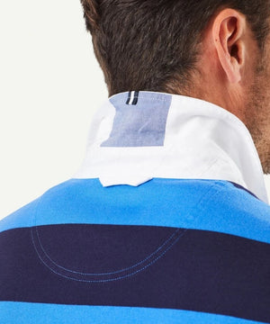 Close-up view of a person's back and neck wearing the **Gazman Block Stripe Rugby** in a regular fit, featuring wide horizontal stripes in shades of blue and a white collar turned up. The visible stitching details and contrasting cotton fabric stand out against the light, plain background.