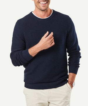 A person wearing a Gazman Textured Cotton Crew in navy blue, paired with a white collared shirt underneath, standing against a plain background. The person is smiling, has a light skin tone, and is casually posing with one hand on the side and the other hand slightly raised.