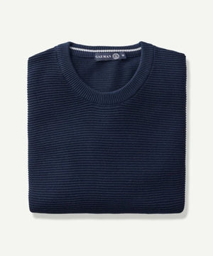 A neatly folded Gazman Textured Cotton Crew in navy blue, crafted from comfortable combed cotton, is shown against a plain background. The ribbed texture adds a touch of elegance, and a small tag at the neckline reads "GAZ MAN".