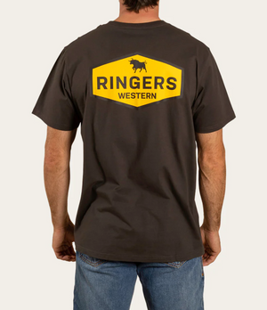 A person wearing a Ringers Western Servo Loose Fit T-Shirt in dark color with a yellow hexagonal logo on the back, featuring a bull silhouette and "RINGERS WESTERN" text. They pair it with blue jeans.