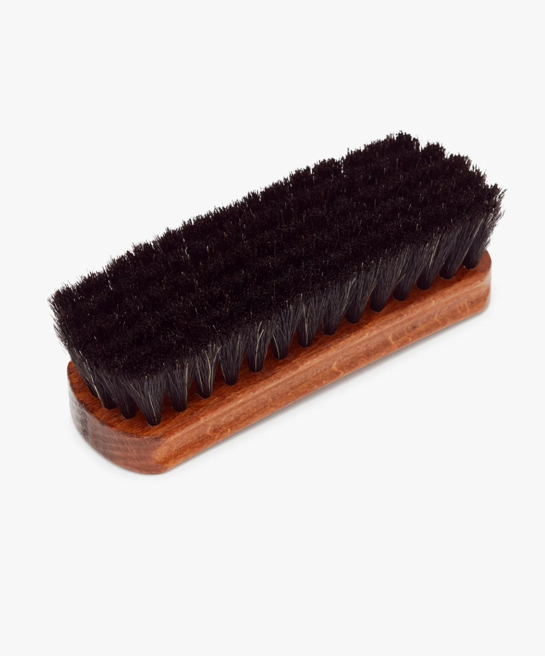 The RM Williams Medium Brush is a rectangular, leather boot brush featuring horse hair bristles on a wooden handle base. Designed for cleaning and polishing shoes, the smooth, polished handle contrasts with the dark bristles. The brush reflects RM Williams craftsmanship and is displayed against a plain white background.