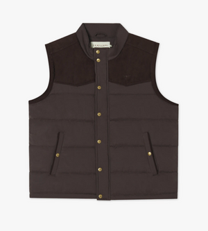 The RM Williams Carnarvon Vest is a brown, sleeveless puffer vest featuring a front snap-button closure and two zippered side pockets. Ideal for trans-seasonal dressing, it boasts a high collar and suede-like yoke detail at the shoulders. The interior tag is visible at the neckline.