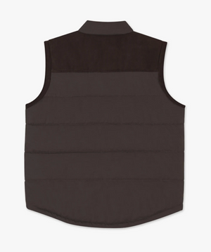 The RM Williams Carnarvon Vest is a dark brown, sleeveless garment featuring a quilted pattern, a collared neck, and a slightly curved hem. The upper back area showcases a darker brown yoke. This lightweight, puffer-style vest is perfect for trans-seasonal dressing and ideal for layering.