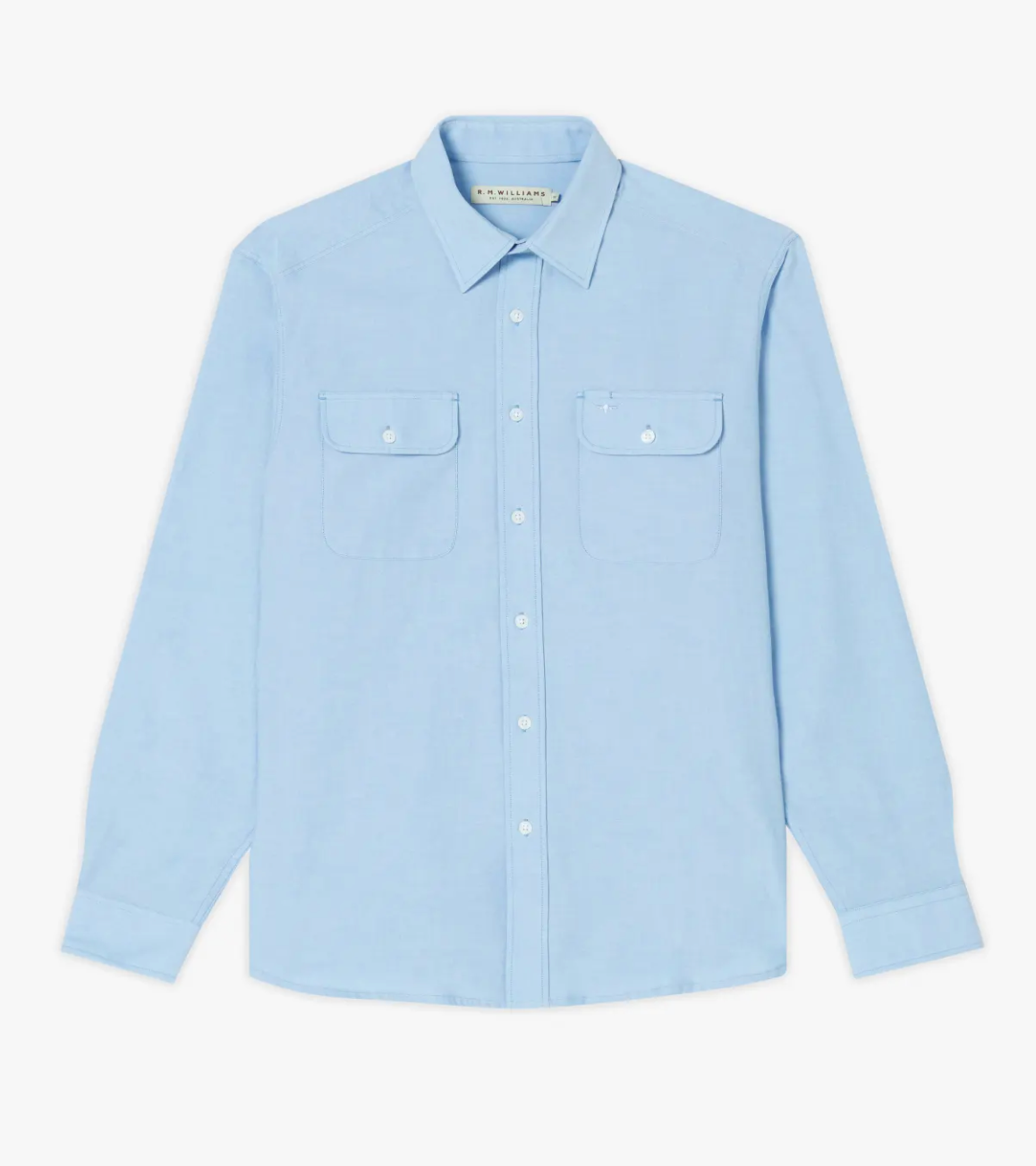 The RM Williams Bourke Shirt is a light blue, long-sleeved, regular fit button-up with a standard collar. Crafted from premium Oxford cotton, it features two breast pockets with flap closures, each secured by a white button. The design is simple and elegant.