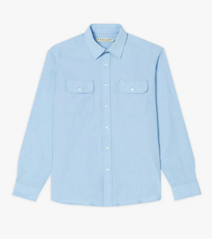The RM Williams Bourke Shirt is a light blue, long-sleeved, regular fit button-up with a standard collar. Crafted from premium Oxford cotton, it features two breast pockets with flap closures, each secured by a white button. The design is simple and elegant.