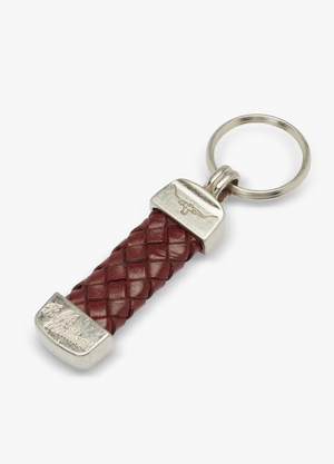 The RM Williams Plaited Key Ring features a silver ring and ends, a maroon braided Kangaroo leather section, and Longhorn embossed designs on the silver ends, adding an elegant touch to its overall look.