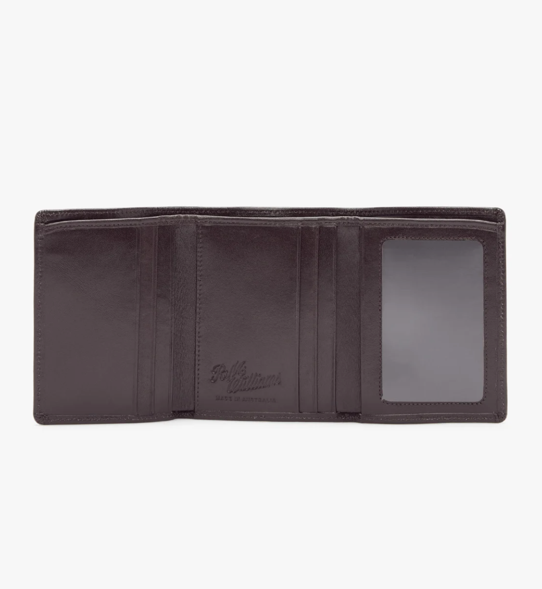 An open RM Williams Trifold Wallet, crafted in dark brown yearling leather, features multiple card slots, an ID window, and a section for bills. The interior is adorned with the embossed R.M.Williams Script logo and branding.