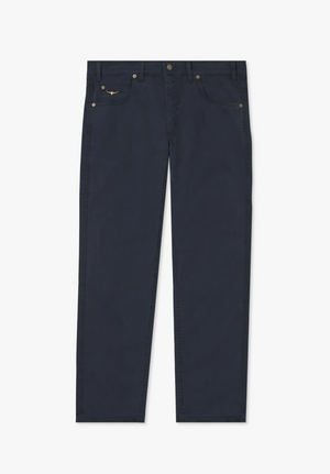 A pair of RM Williams Linesman Cotton Jeans displayed flat on a white background. The dark blue, slim fit jeans feature a straight-leg cut, brass rivets, and classic five-pocket styling, including a small logo on the front right pocket. Made from stretch cotton twill for added comfort.