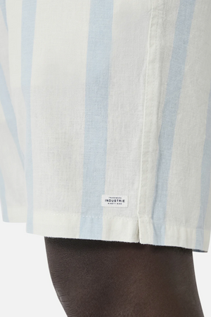 A person wears Industrie The Mykonos Short in light blue and white stripes, showcasing an elasticized waist and an Industrie patch detail against a plain backdrop.