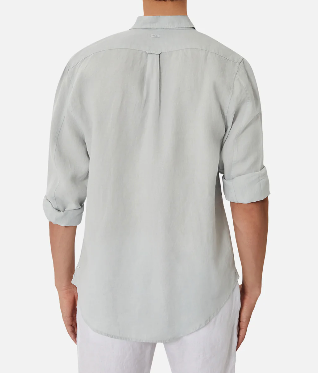 Back view of a person wearing Industrie The Tennyson Linen Shirt, a relaxed fit light grey long sleeve shirt made from 100% linen with rolled-up sleeves, paired stylishly with crisp white pants against a plain white background.
