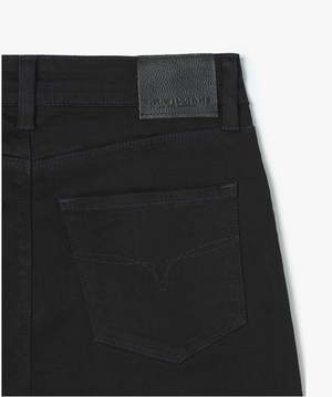 Close-up shot of the back pocket of a pair of RM Williams Albury Jean in black. The pocket features minimalist stitching, and there is a leather patch with text on the waistband above it. Made from stretch cotton, these high-rise skinny fit jeans also showcase subtle Longhorn embroidery for a touch of flair.