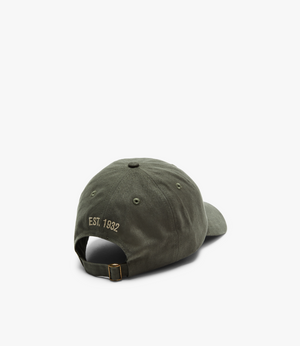 The RM Williams Mini Longhorn Cap in green, made from cotton twill, displays "EST. 1932" embroidered in gold on the back and includes an adjustable buckle strap, all set against a white background.