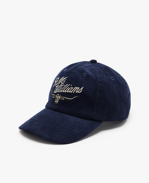 A dark blue RM Williams Corduroy Longhorn Cap in cotton corduroy, featuring beige "R.M. Williams" script and an embroidered longhorn emblem, is displayed on a plain white background, offering a stylish nod to classic elegance.