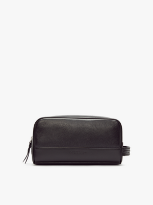 The RM Williams City Washbag features a black full grain leather exterior with a pebbled texture and a smooth lower panel. It boasts a zipper closure on top and a small handle on the side. Spacious and sleek, this minimalist toiletry bag is perfect for carrying your essentials.