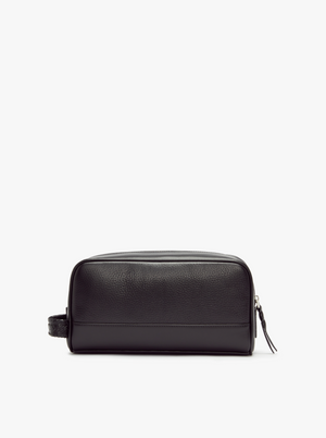 The RM Williams City Washbag is a black, full-grain leather toiletry bag featuring a side handle and zippered closure. This spacious travel washbag has a rectangular shape with a smooth, textured finish and is displayed against a white background.