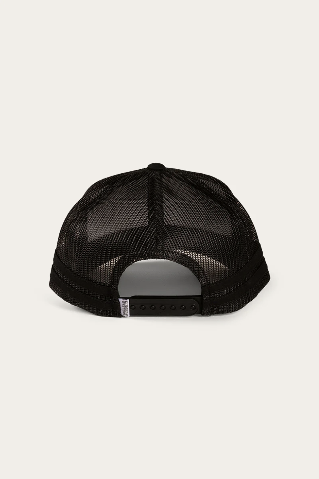 The Ringers Western Deacon Trucker Cap is displayed from the back, showcasing a black mesh design with a plastic snapback closure. A curved brim and side label enhance its style against a plain off-white background.