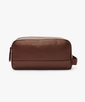 The RM Williams City Washbag is crafted from brown full grain leather and features a zipper closure on top, along with a side handle. This washbag by R.M.Williams boasts a smooth, minimalist design with subtle embossing near the bottom.