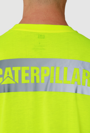 A person is seen from the back wearing the CAT Triton Block Tee, a bright yellow cotton shirt with a reflective strip and the word "CATERPILLAR" in bold. It features moisture-wicking properties for comfort.