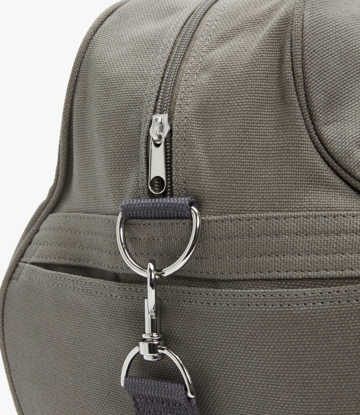 Close-up of the RM Williams Nanga Canvas Bag in gray, featuring a zipper and metal attachment rings on the side. The duffle-style strap connects to these rings, showcasing the bag's detail and design.
