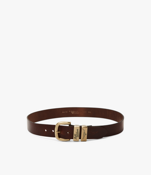 The RM Williams Drover Belt is a dark brown belt featuring an antique brass buckle and a distinctive metal clasp. Made from vegetable-tanned leather, it showcases embossed text details and multiple holes for size adjustment. The design is minimalistic, with the belt laid flat in a circular shape.
