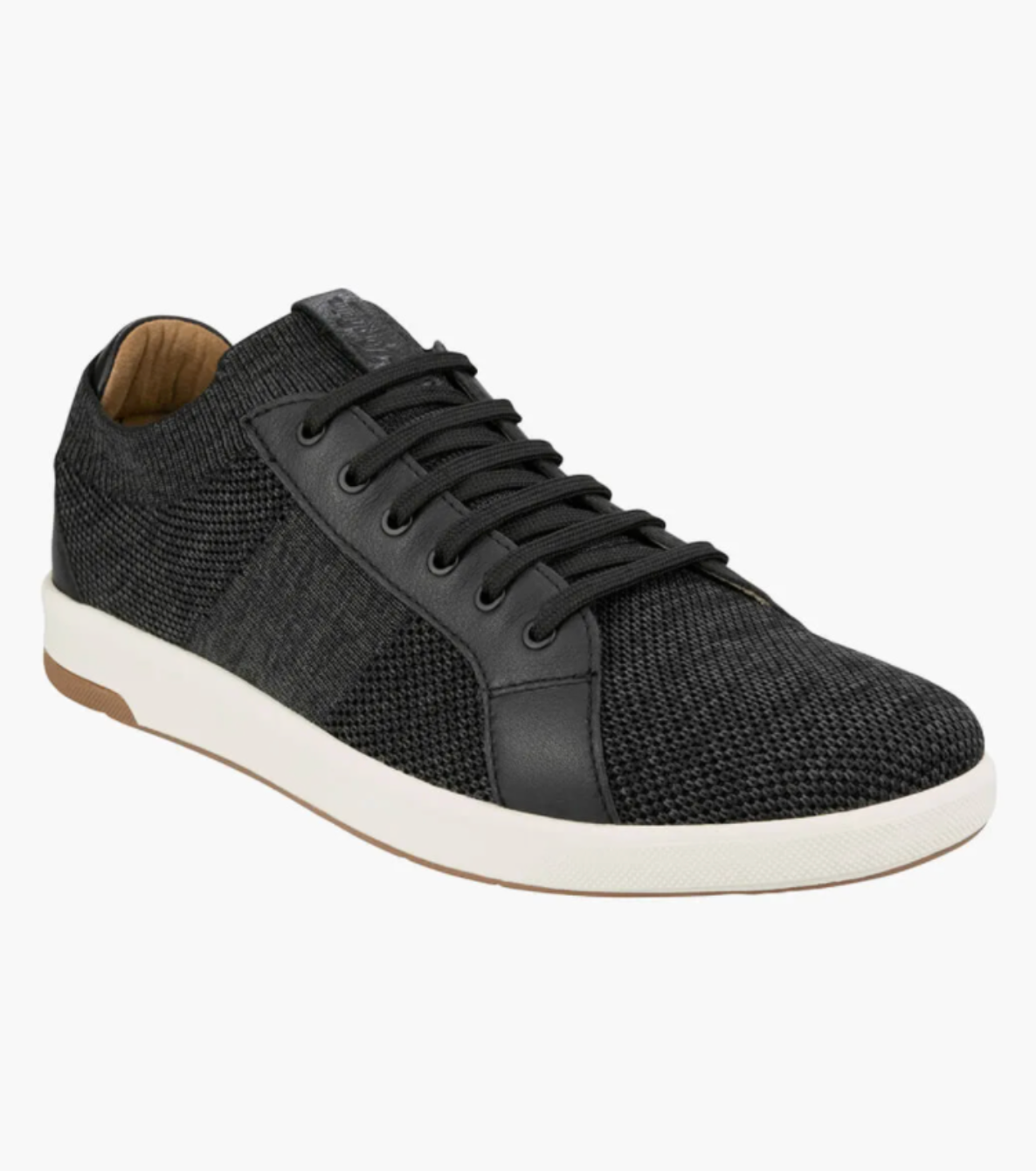 The Florsheim Crossover Knit is a black lace-up sneaker featuring a textured fabric and leather upper, a white rubber sole, and brown inner lining. With a cushioned footbed, it's designed for casual comfort suitable for everyday wear.