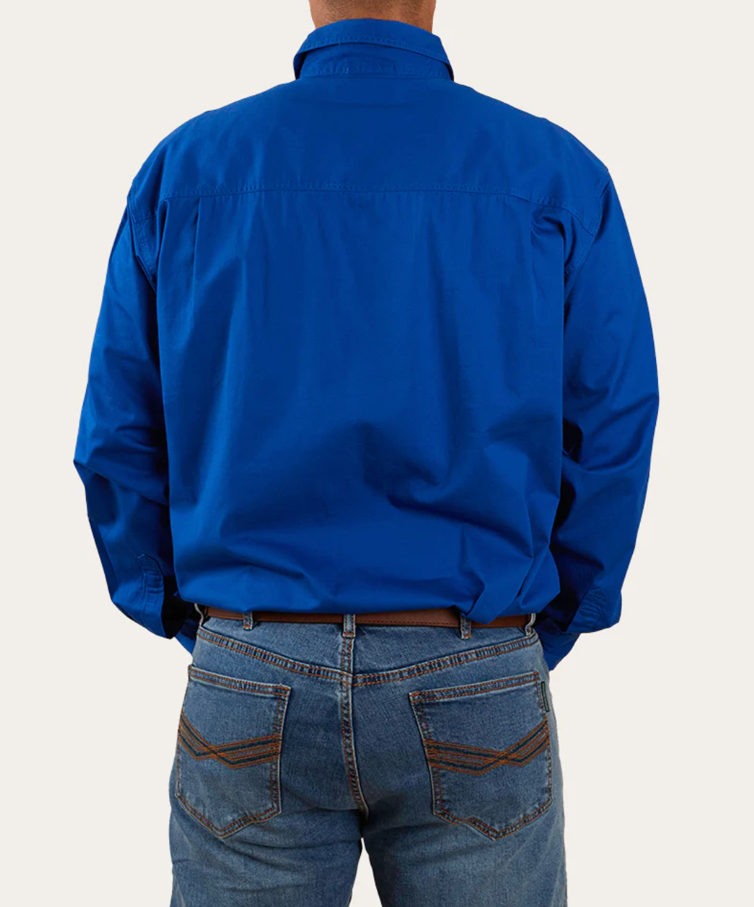 A person in a bright blue Ringers Western King River Half Button long-sleeve work shirt and cotton blue jeans stands with their back to the camera, shirt neatly tucked into the jeans, against a plain white background.