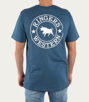 Wearing a blue Ringers Western Signature Bull Classic T-Shirt, adorned with the iconic bull logo on the back and crafted from pre-shrunk cotton, a person pairs it stylishly with blue jeans against a plain beige backdrop.