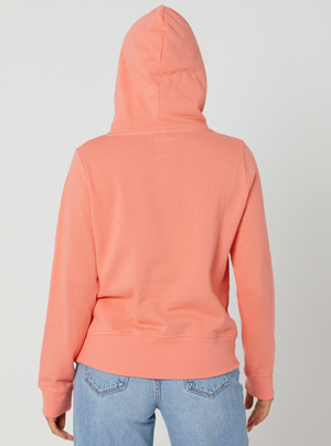 Rear view of a person wearing the Rip Curl Script II Hood in coral, with the hood up, paired with light blue jeans against a plain white background.