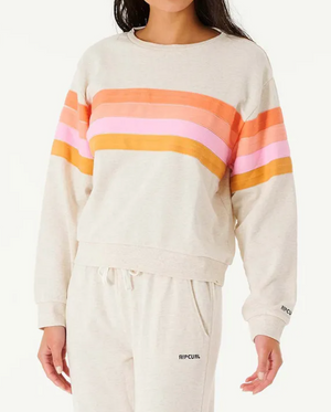 Dressed in the Rip Curl Day Break Crew, a light gray sweatshirt with orange, pink, and red stripes, a person exudes relaxed fit fashion. Paired with matching sweatpants, this outfit captures Rip Curl's signature laid-back style with its comfortable crew neck design.