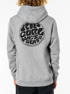 A person with curly hair, seen from the back, is wearing a grey Rip Curl Wetsuit Icon Hood with black text on the back that reads "Rip Curl Wetsuits" inside a circular design. Below the circle, it lists locations: "Torquay, Trestles, Hossegor.
