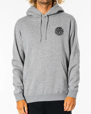 A person with curly hair wears a comfortable light gray Rip Curl Wetsuit Icon Hood, featuring a small circular logo on the left chest that reads "For sure future surf" in black text. The Organic Cotton hoodie has drawstrings, and the individual wears dark pants. The background is plain white.