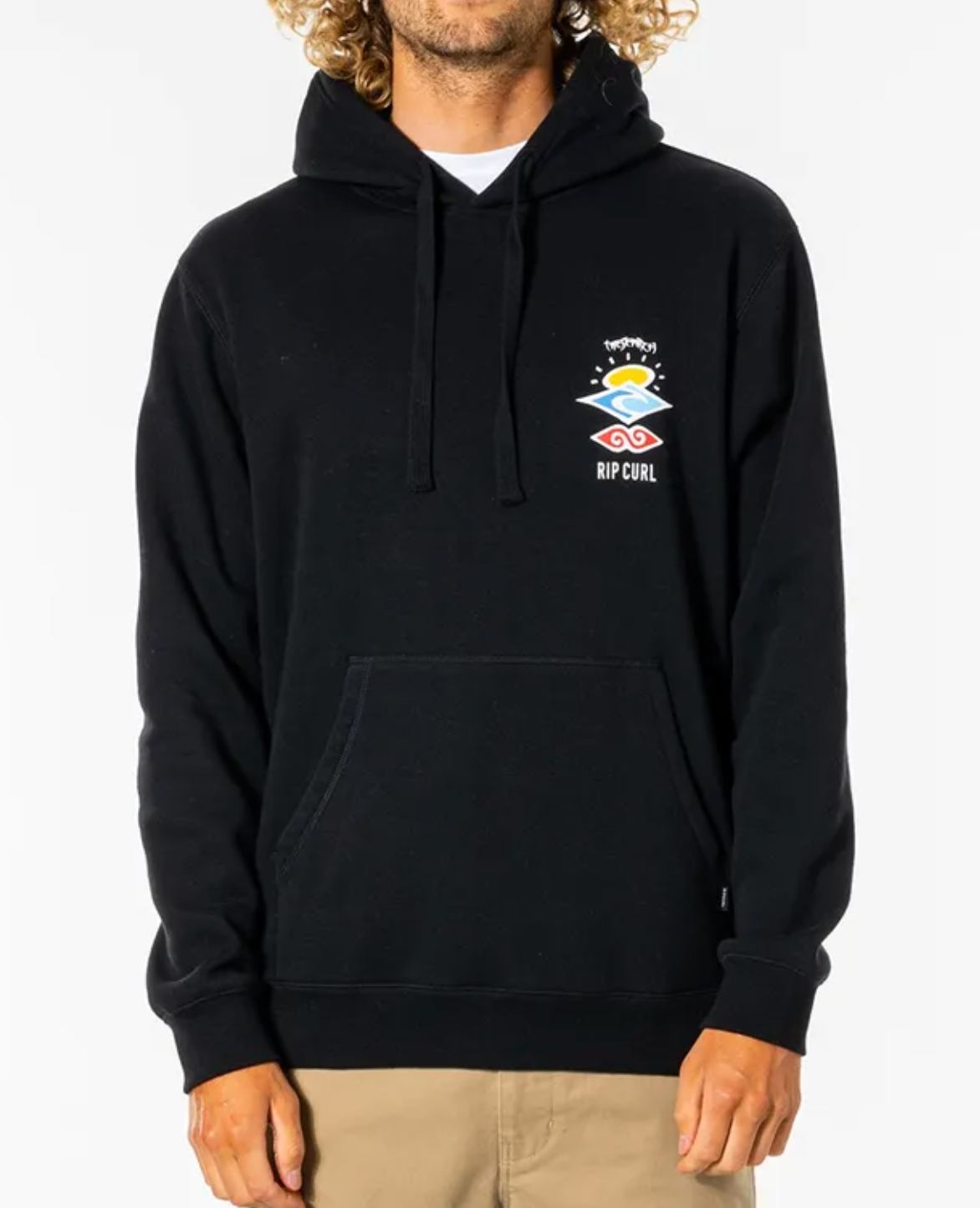 A person wearing a comfortable Rip Curl Search Icon Hood with the logo on the chest and light brown pants. The black hoodie, made of organic brushed cotton, features a front pocket and drawstrings at the neck. The person has curly blonde hair and is standing against a plain white background.