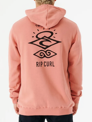 A person stands against a white background, wearing the Rip Curl Search Icon Hood. It's crafted from organic brushed cotton, featuring black abstract designs on pink fabric and a soft fleece lining for comfort, with "Rip Curl" emblazoned on the back.