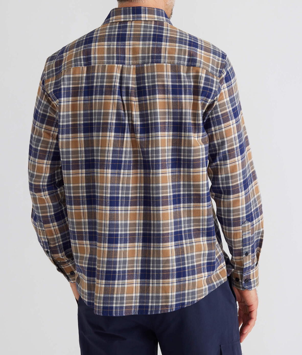 Wearing a Breakaway Ford Cotton Brush Shirt, with its cozy long-sleeve plaid design and shades of blue, brown, and white, a person faces away from the camera. The 100% cotton shirt complements their navy blue pant-pocketed hand against a plain white backdrop.