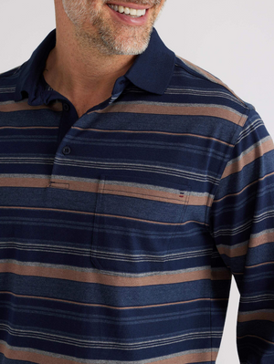 A person smiles in a Breakaway Wallux Kinnersly Jersey Polo featuring a relaxed-fit navy blue and brown striped design. Its long sleeves pair well with the buttoned collar and chest pocket. The background is plain and light-colored.