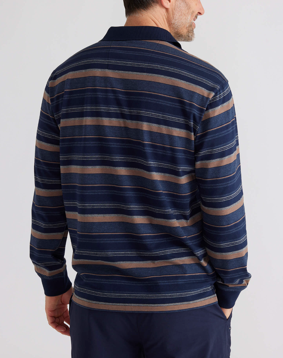 A person wearing the Breakaway Wallux Kinnersly Jersey Polo with dark blue, brown, and gray stripes is shown from the back. They have short hair and pair it with dark pants.