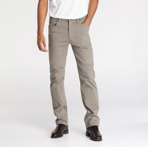 Someone wearing light gray Wrangler Classics Straight Moleskin Jeans, a white shirt, and dark brown shoes stands against a plain white background with one hand in their pocket.